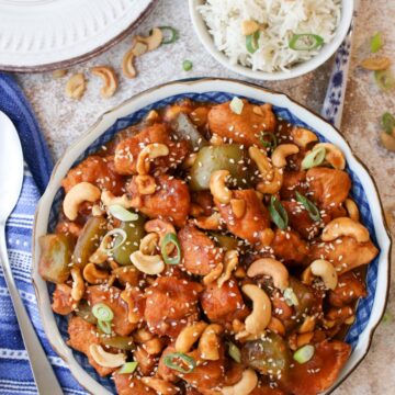 Serving bowl filled with cashew chicken with rice in a bowl on the side