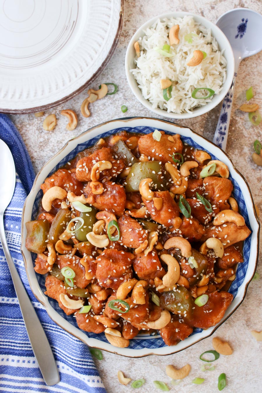 Serving bowl filled with cashew chicken with rice in a bowl on the side