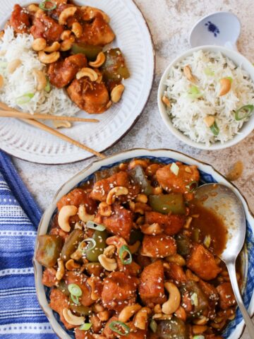 Serving bowl filled with cashew chicken with rice in a bowl on the side