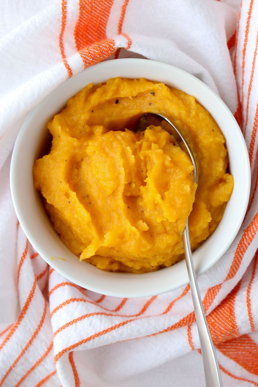butternut squash puree in a white bowl surrounded by an orange and white towel
