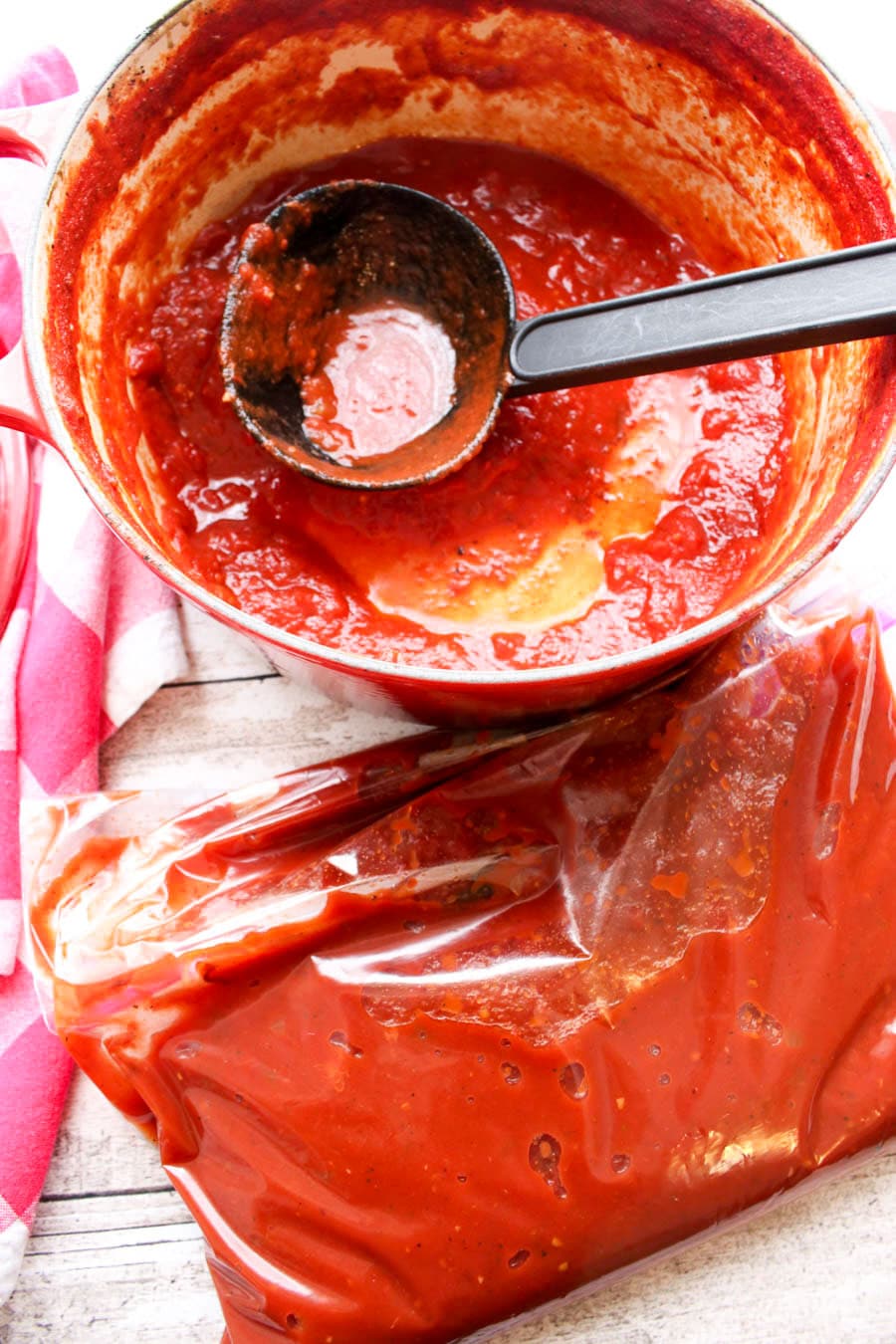 Pot of red spaghetti sauce being ladled into a zip top bag