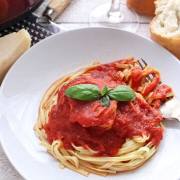 Spaghetti topped with red sauce and fresh basil