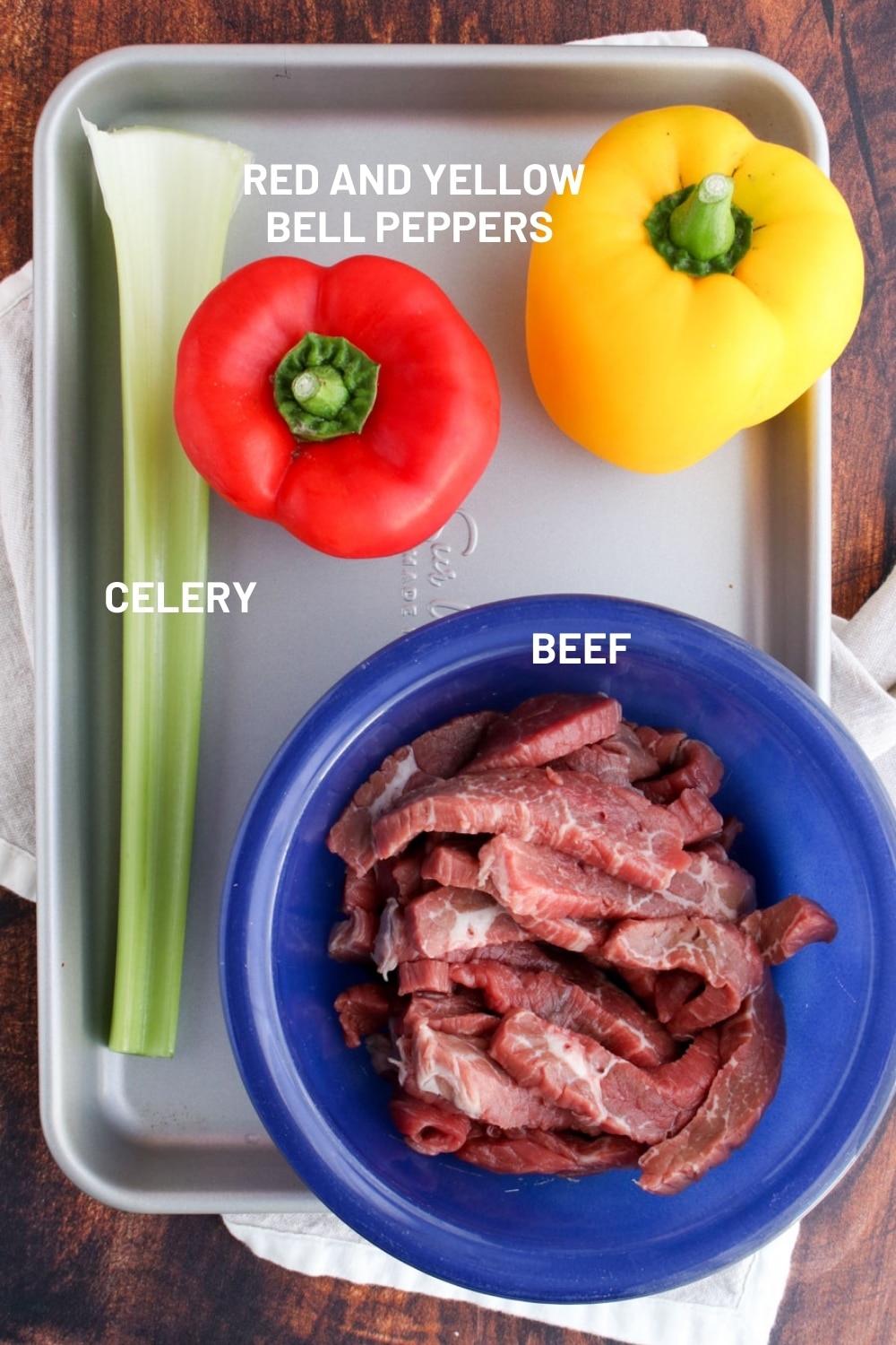 A bowl of beef strips, red and yellow bell pepper, and celery stalk