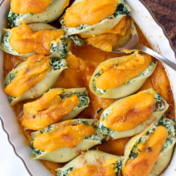 Casserole dish filled with stuffed shells topped with orange squash