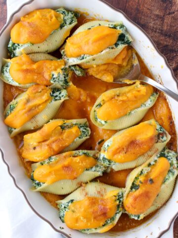 Casserole dish filled with stuffed shells topped with orange squash