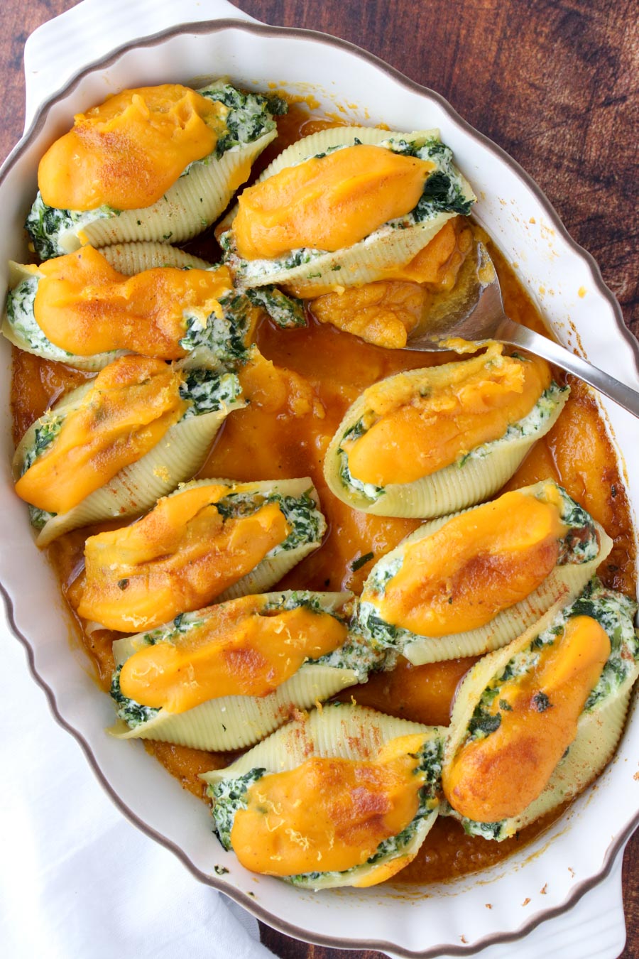 Casserole dish filled with stuffed shells topped with orange squash