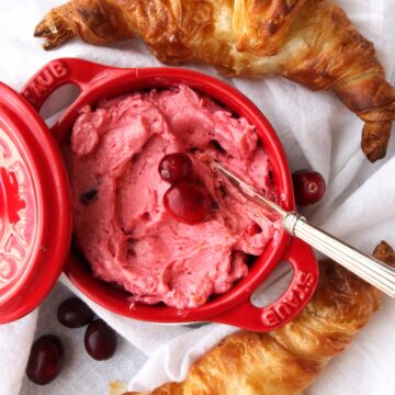 Dish with pink cranberry butter and two croissant