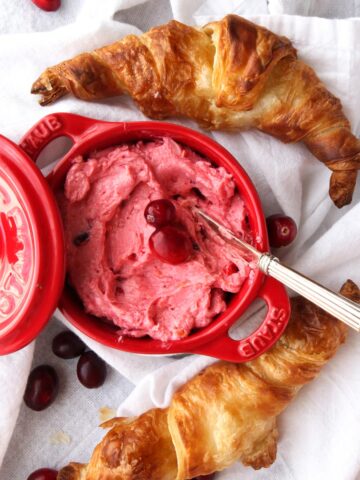 Dish with pink cranberry butter and two croissant