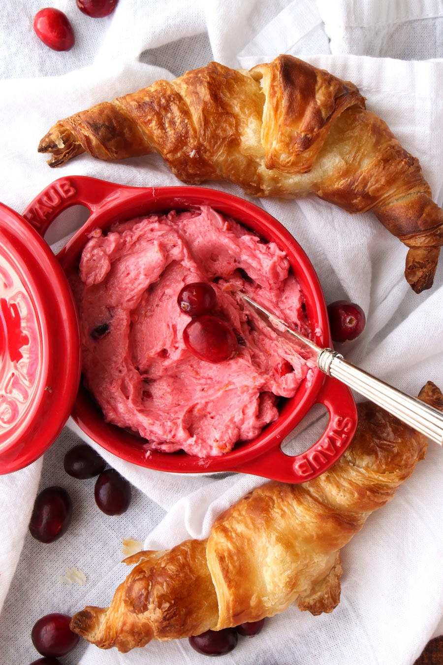 Dish with pink cranberry butter and two croissant