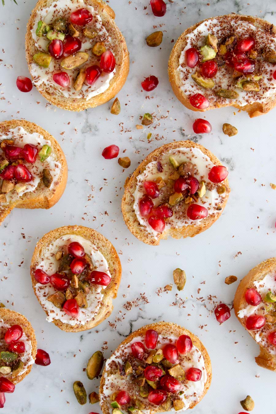 Small toast rounds topped with cream cheese, nuts, and pomegranate seeds