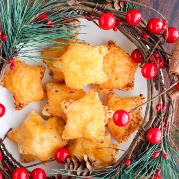 Cheese stars on a play with surrounded by Christmas decorations of holly and pine