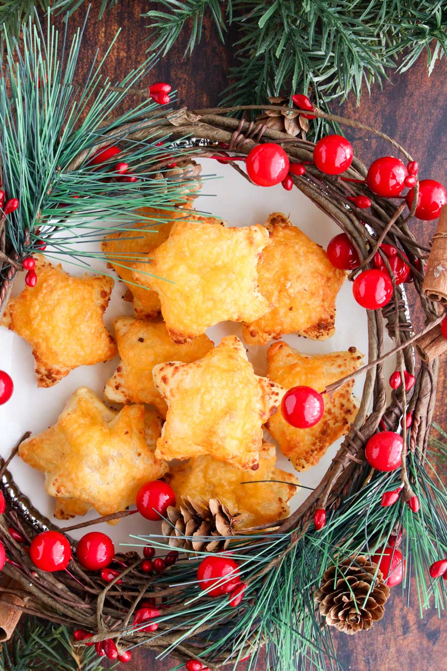 Cheese stars on a play with surrounded by Christmas decorations of holly and pine