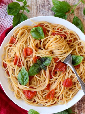 Bowl of pasta with tomatoes and pasta swirled around a fork