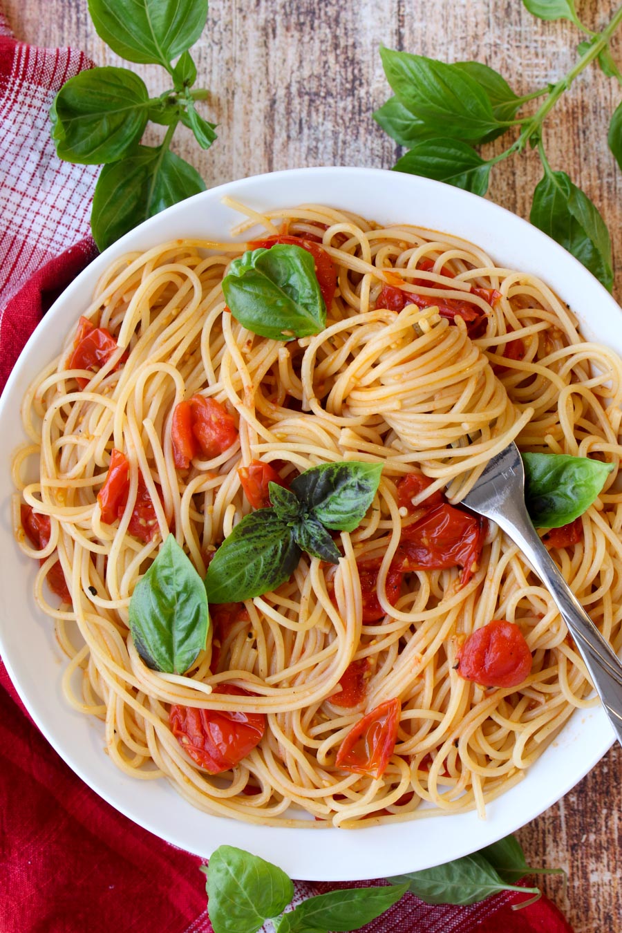 Bowl of pasta with tomatoes and pasta swirled around a fork