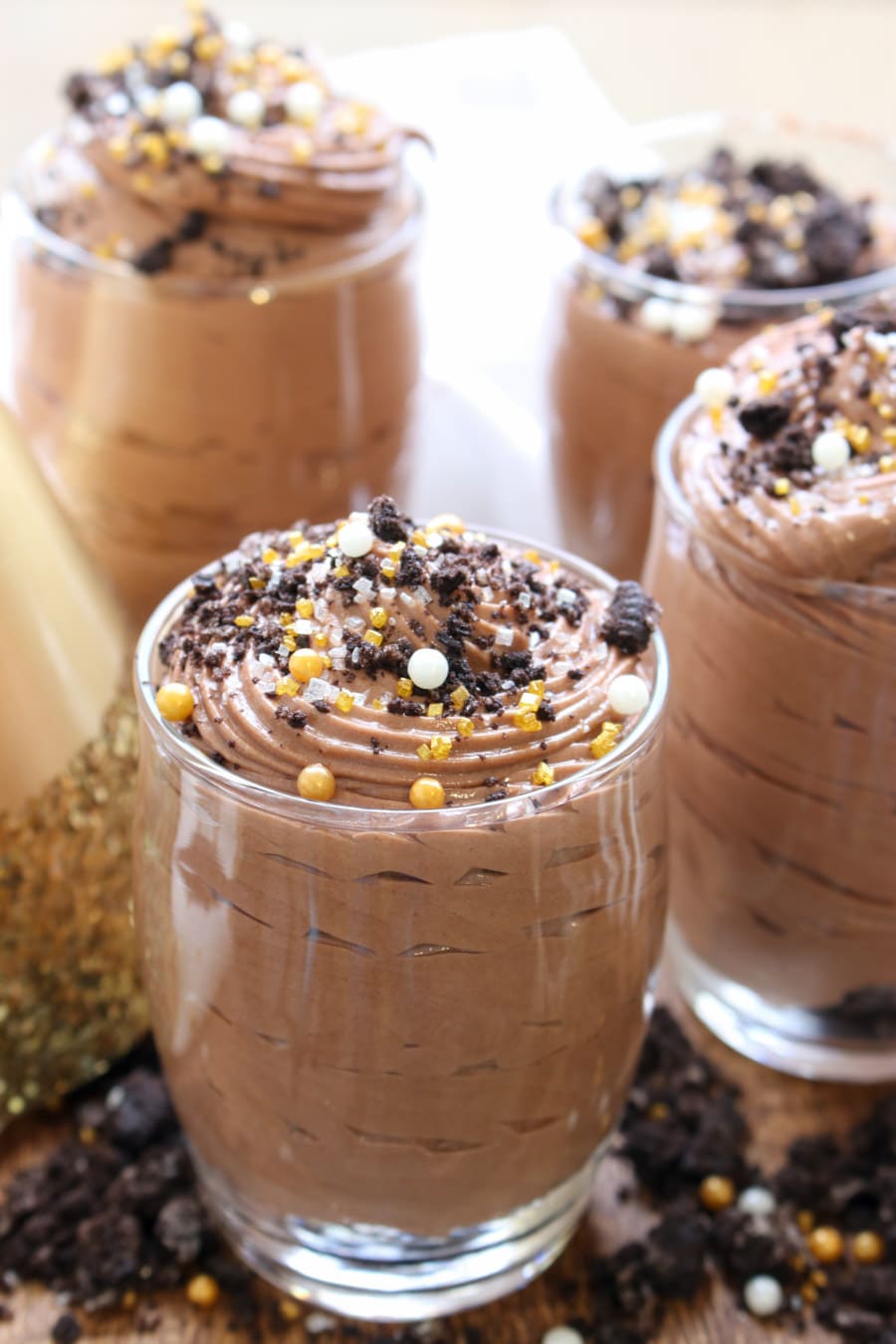 Four dessert glasses filled with chocolate hazelnut mousse with gold sprinkles on top