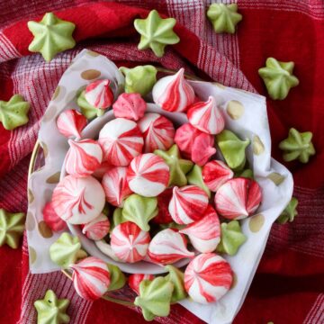 A bowl of colorful meringues on a red cloth