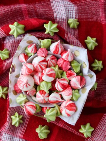 A bowl of colorful meringues on a red cloth