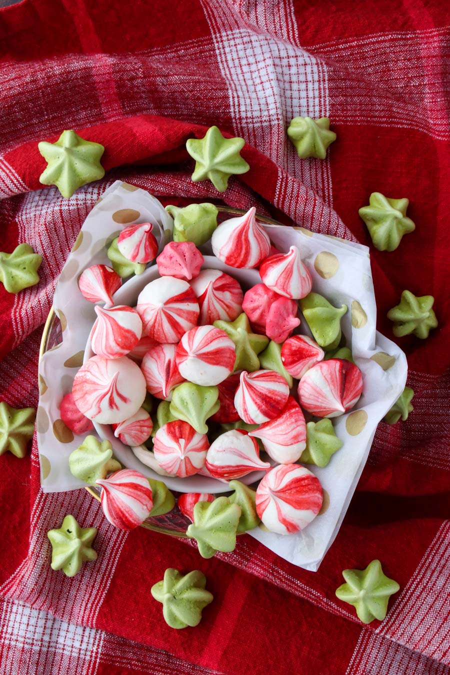 A bowl of colorful meringues on a red cloth