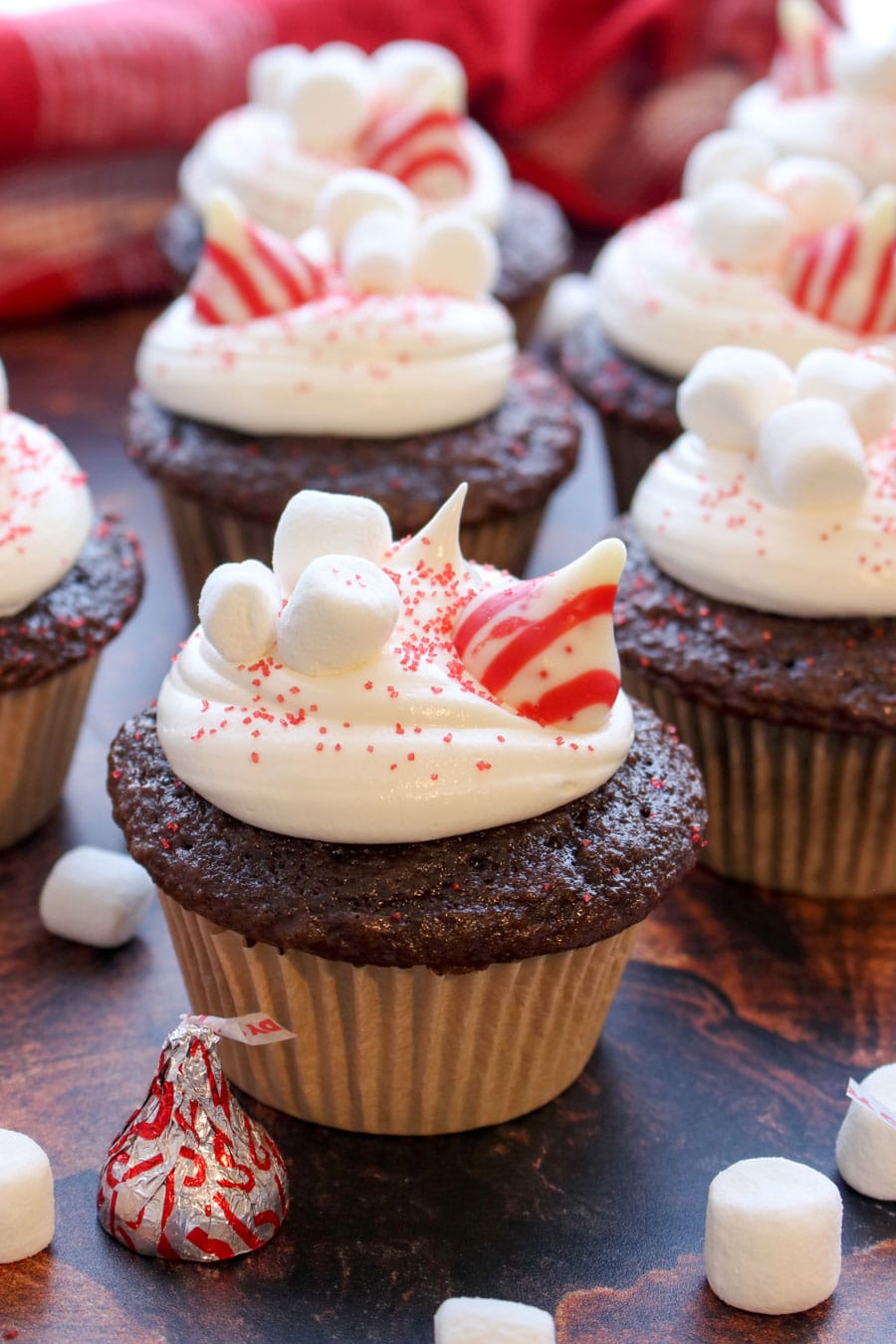 chocolate cupcake with white frosting topped with stripped candy kisses and marshmallows