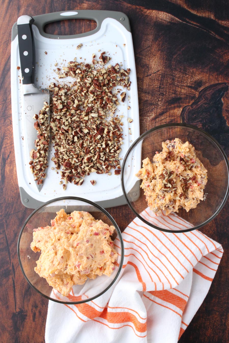 Pimento cheese in a bowl with a cookie sheet of chopped pecans