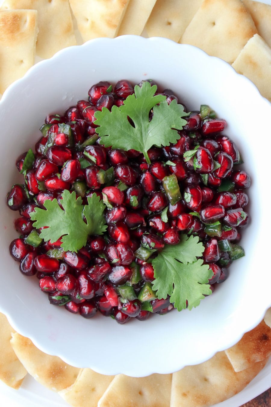 white bowl filled with pomegranate and three cilantro leaves