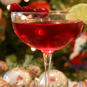 Scarlet colored cocktail in from of a Christmas tree