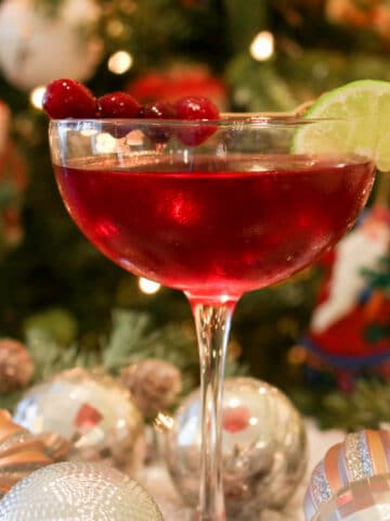 Scarlet colored cocktail in from of a Christmas tree