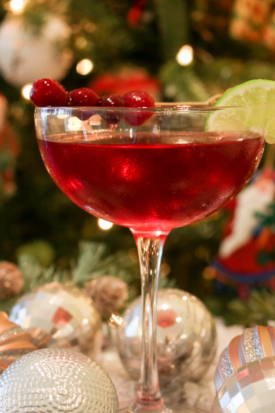 Scarlet colored cocktail in from of a Christmas tree