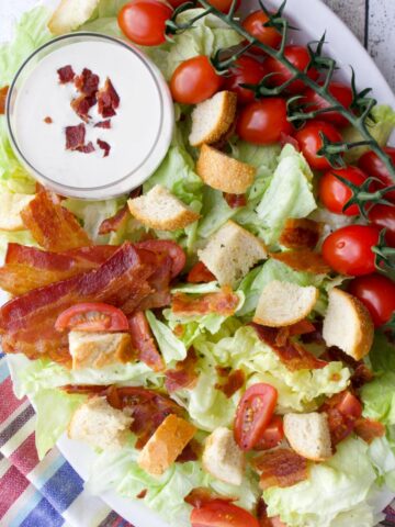 Platter of lettuce, tomatoes, bacon, croutons, and dressing