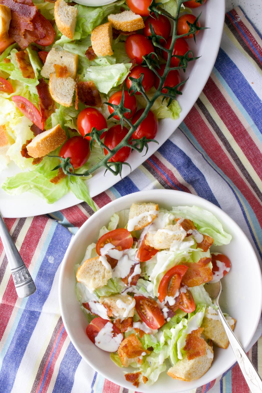 small bowl of salad next to the larger platter of salad sitting on a red, white, blue cloth