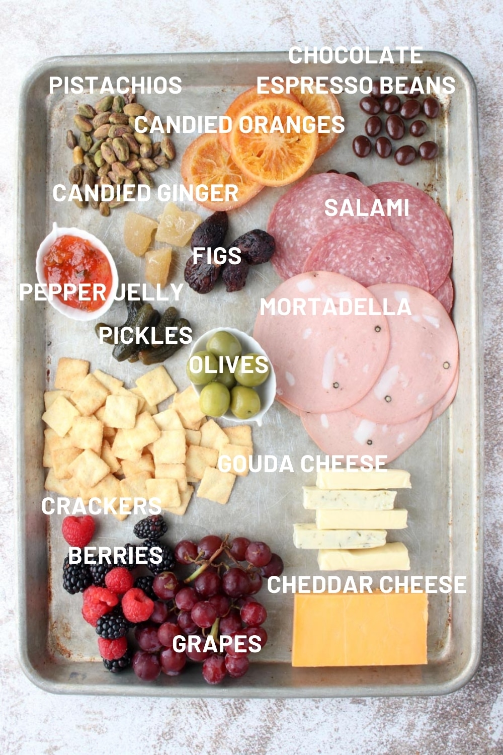 A sheet pan with all of the ingredients need to make a charcuterie platter for two.