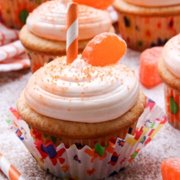 Orange cupcakes with a slice of candy and a straw on top