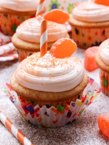 Orange cupcakes with a slice of candy and a straw on top