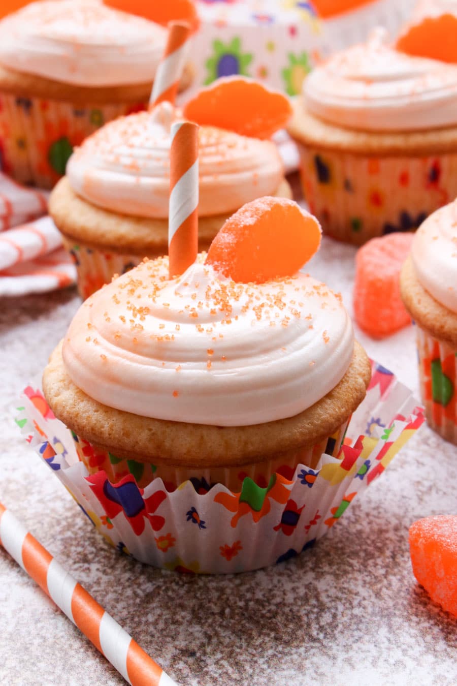 Orange cupcakes with a slice of candy and a straw on top