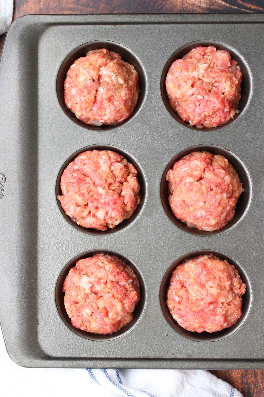 muffin tin with raw meatloaves