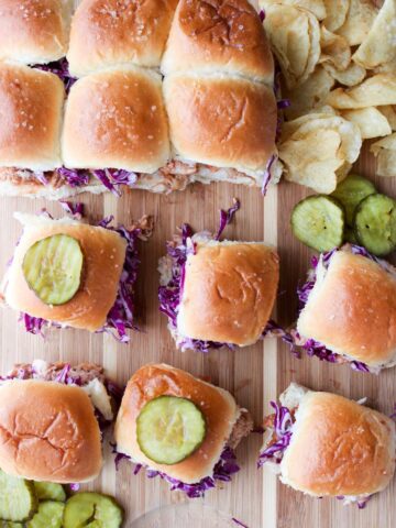 BBQ Sliders on a serving board with pickles and chips