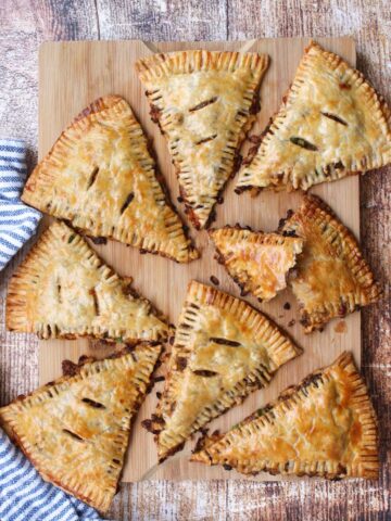 8 beef and potato hand pies on a cutting board