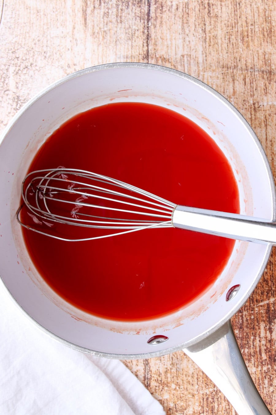 White pan with blood orange glaze and a whisk