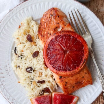 Salmon filet with sliced blood orange on top with a side of rice