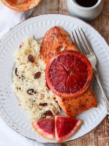 Salmon filet with sliced blood orange on top with a side of rice