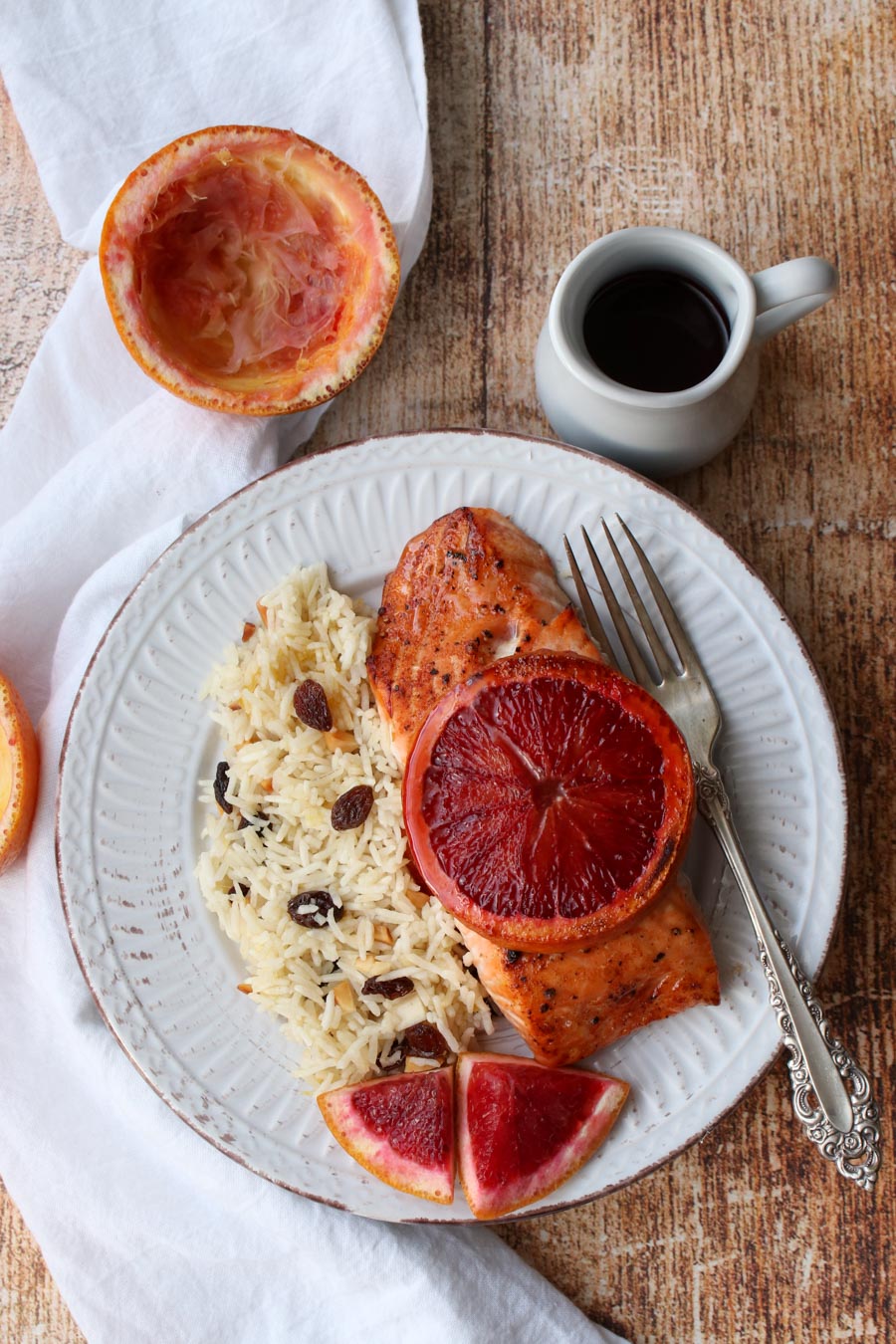 plate of salmon with orange slice on top and side of rice