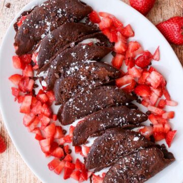 a platter of chocolate tacos surrounded by diced strawberries