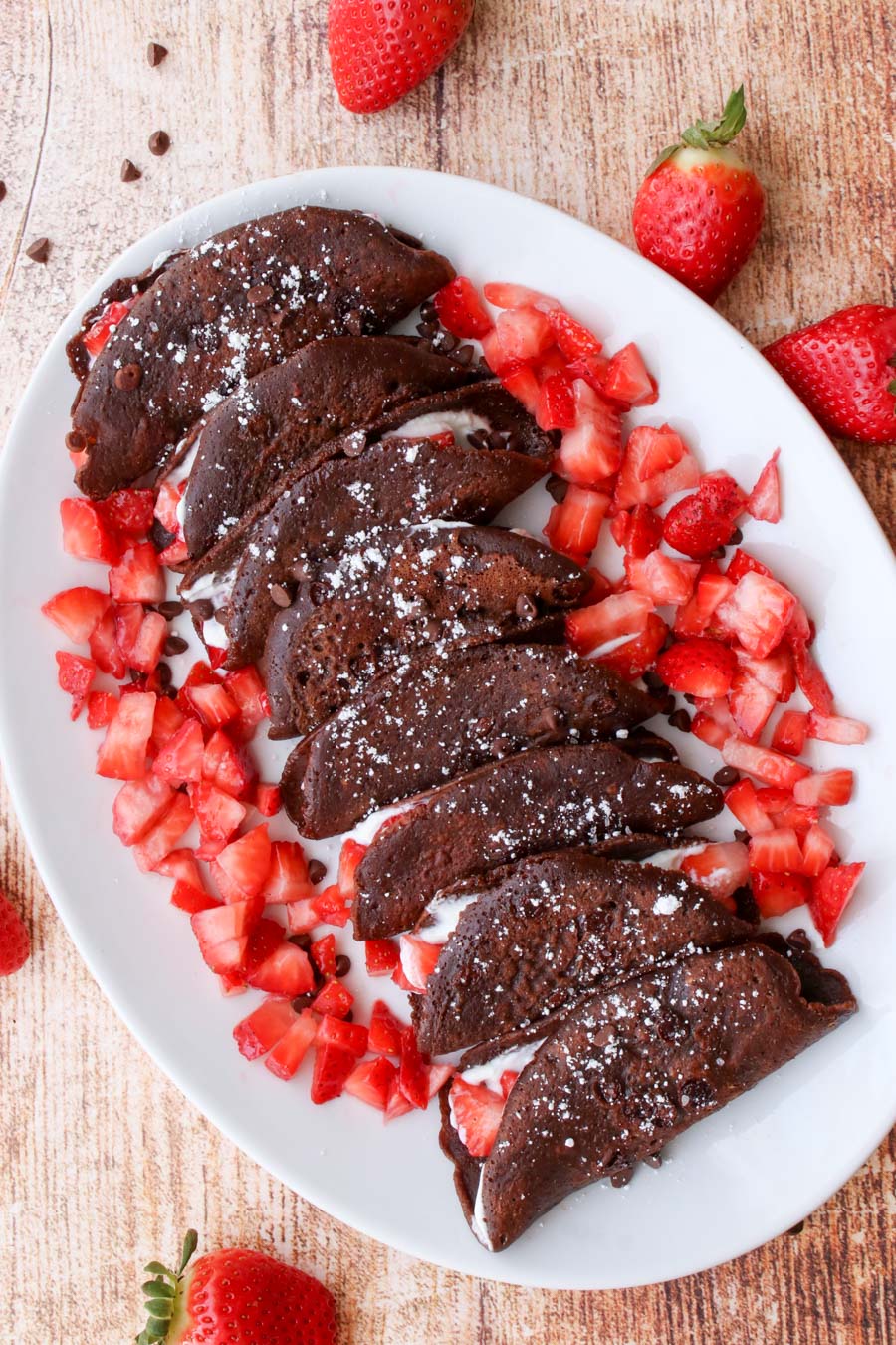 a platter of chocolate tacos surrounded by diced strawberries