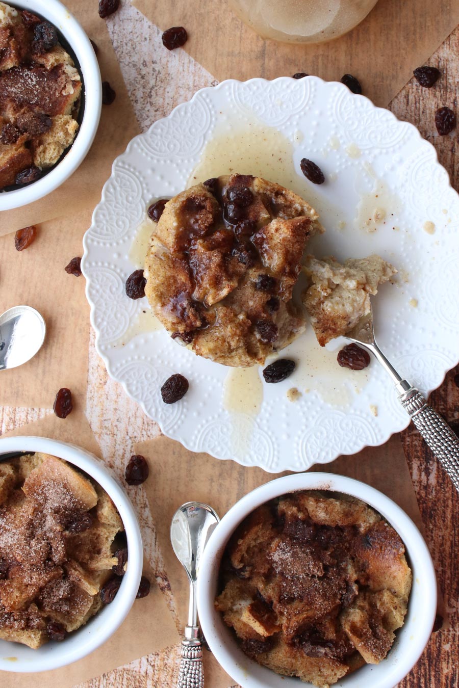 Overhead shot of bread budding on a white plate with a fork and raisins