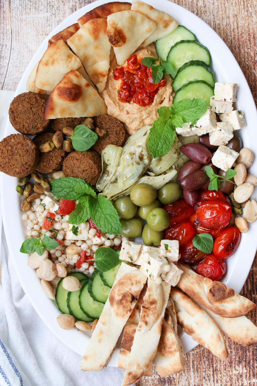 Platter of assorted Mediterranean foods on a large white oval plate