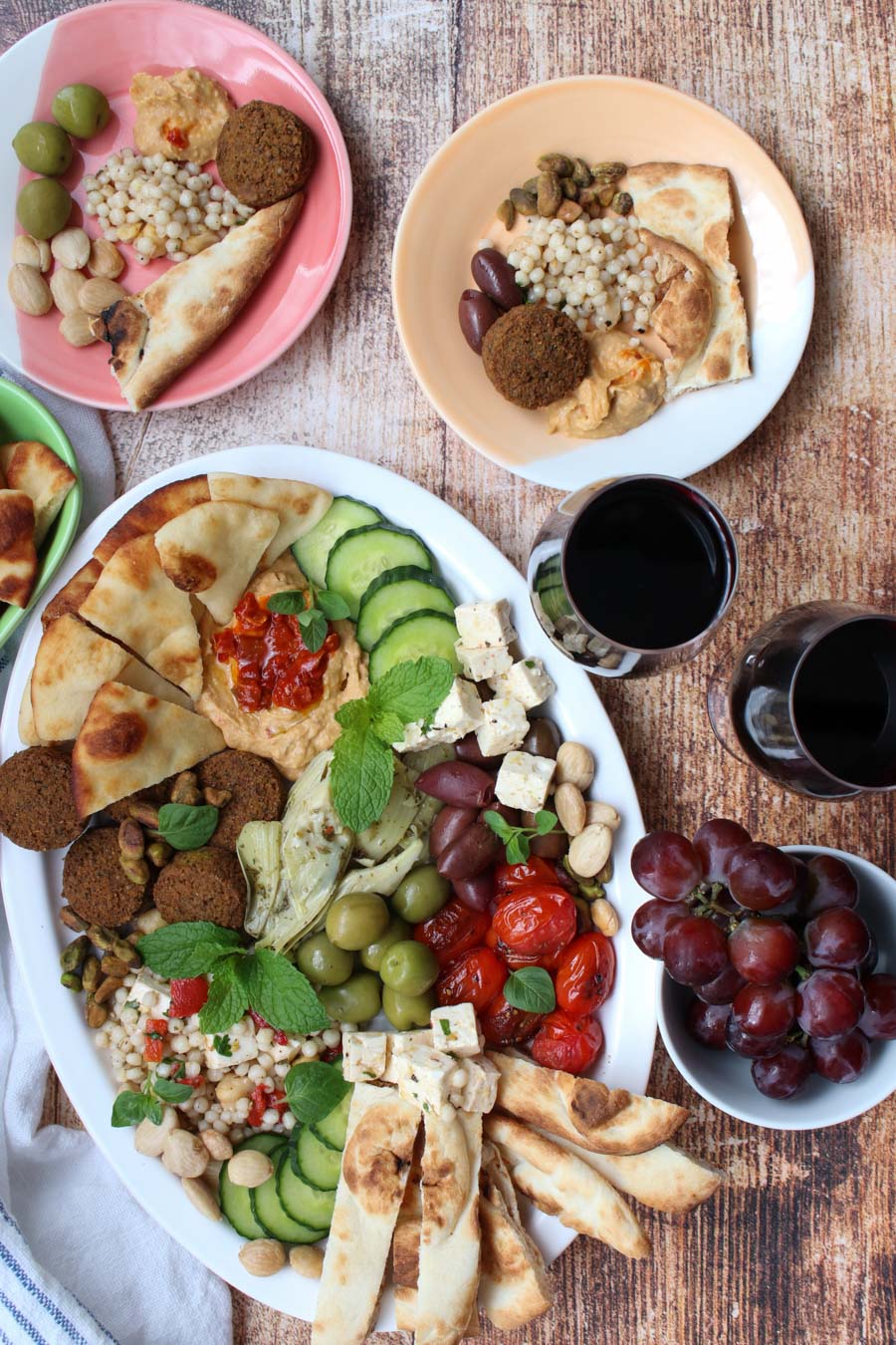 overhead shot of a mezze platter, two glasses or wine, and small plates