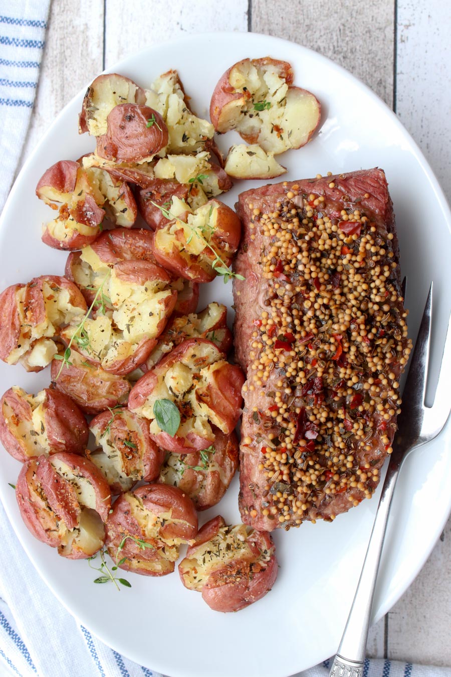 CORNED BEEF BRISKET AND SMASHED POTATOES ON A WHITE SERVING PLATE