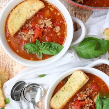 two bowls of sausage and bean soup with large croutons