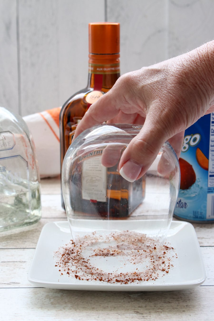 rim of glass being dipped into mixture of salt and chili powder