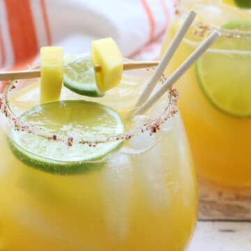 glass of mango margarita with garnish and straws